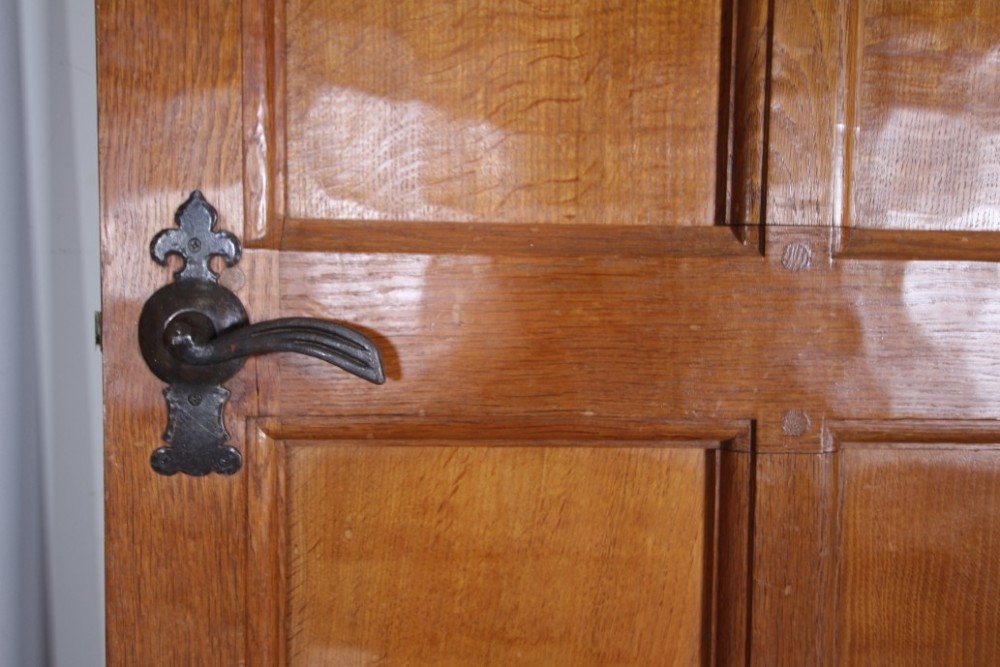 A solid oak interior door featuring ten raised panels, a hand-adzed textured finish, wrought iron latch hardware, and a carved mouse detail. View IX