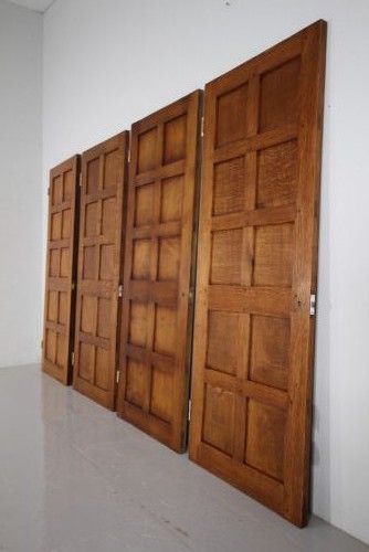 A solid oak interior door featuring ten raised panels, a hand-adzed textured finish, wrought iron latch hardware, and a carved mouse detail. View VI