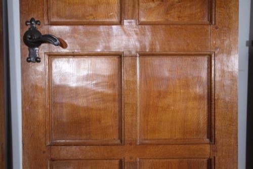 A solid oak interior door featuring ten raised panels, a hand-adzed textured finish, wrought iron latch hardware, and a carved mouse detail. View III