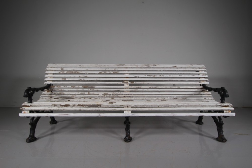 A 19th-century garden bench featuring black cast iron frame ends moulded in a branch pattern with weathered white painted wooden slats forming the backrest and seat. View III