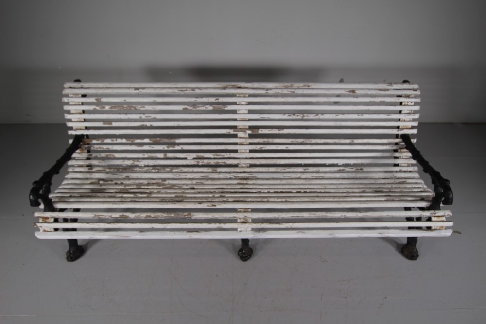 A 19th-century garden bench featuring black cast iron frame ends moulded in a branch pattern with weathered white painted wooden slats forming the backrest and seat. View IV