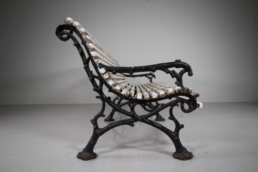 A 19th-century garden bench featuring black cast iron frame ends moulded in a branch pattern with weathered white painted wooden slats forming the backrest and seat. View VIII