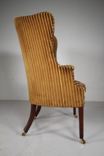 A Georgian style high back barrel armchair upholstered in striped gold velvet, featuring square tapered mahogany front legs on brass castors. View V