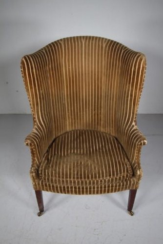 A Georgian style high back barrel armchair upholstered in striped gold velvet, featuring square tapered mahogany front legs on brass castors. View VI