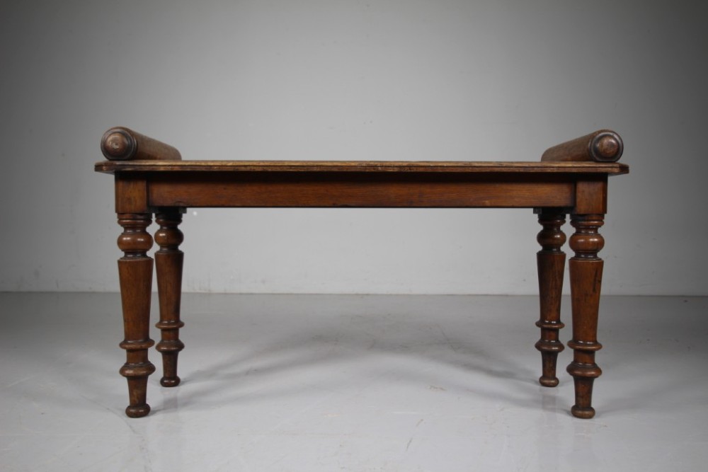 A 19th-century English oak window seat featuring cylindrical bolster armrests and four turned legs. View II