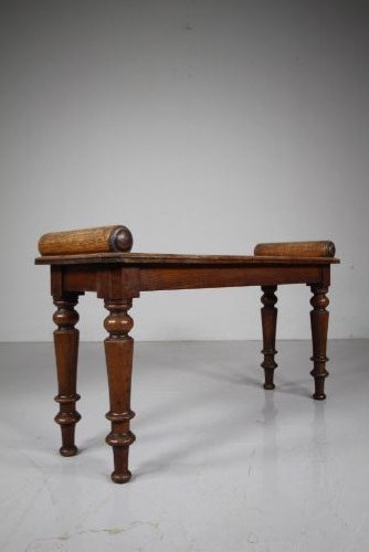 A 19th-century English oak window seat featuring cylindrical bolster armrests and four turned legs. View V
