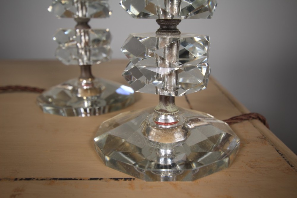 A pair of 1920s English cut glass table lamps featuring stacked faceted glass elements on round cut bases with dark metal lamp holders. View V