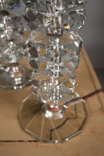 A pair of 1920s English cut glass table lamps featuring stacked faceted glass elements on round cut bases with dark metal lamp holders. View II