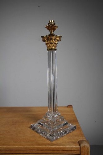 A tall 19th-century clear cut-glass table lamp featuring a fluted column, stepped square base, and an ornate gilt brass Corinthian capital.
