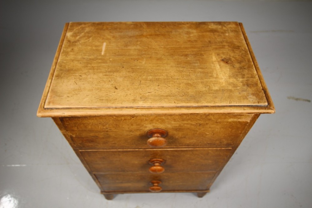 A Georgian painted pine chest of drawers featuring three drawers with wooden knobs and shaped cut-out feet. View II