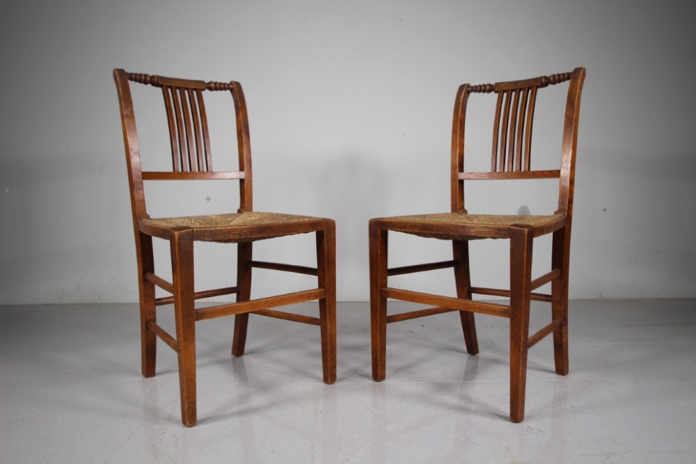 A set of six early 19th-century elm country dining chairs featuring vertical slat backs, turned bobbin top rails, and woven rush seats. View VII