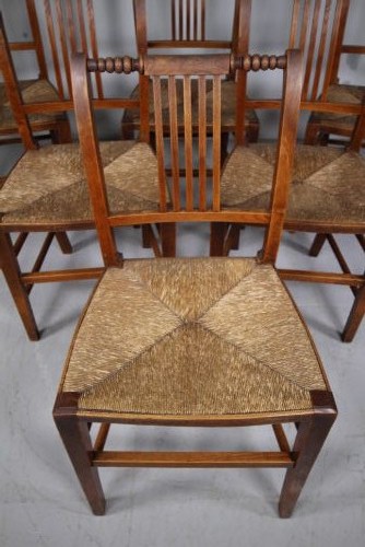 A set of six early 19th-century elm country dining chairs featuring vertical slat backs, turned bobbin top rails, and woven rush seats. View VI