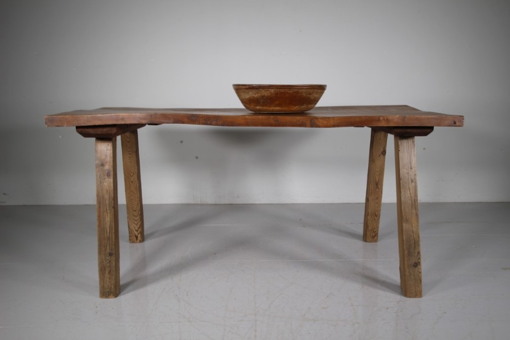 An early 19th century primitive dining table crafted from timber featuring a thick slab top and splayed legs. View IV