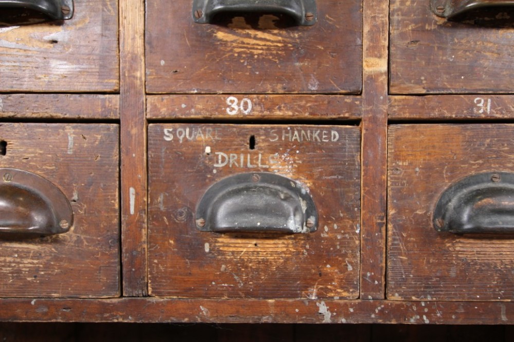 A large 19th-century pine bank of drawers featuring thirty-five small drawers with metal cup handles, top pigeonhole compartments, open bottom shelving, and a dark painted outer frame. View II