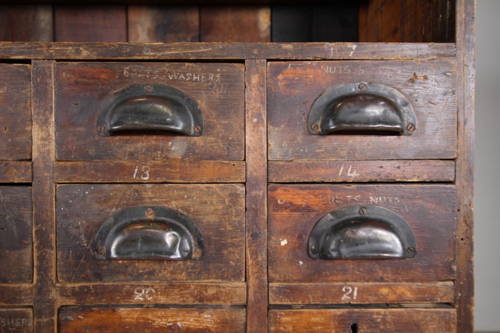A large 19th-century pine bank of drawers featuring thirty-five small drawers with metal cup handles, top pigeonhole compartments, open bottom shelving, and a dark painted outer frame. View III