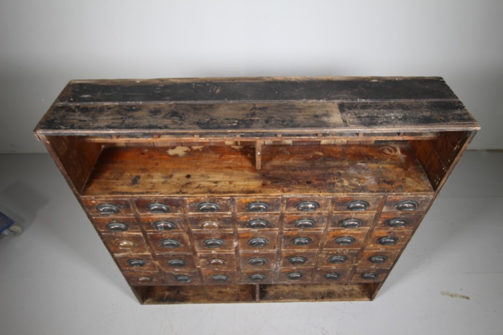 A large 19th-century pine bank of drawers featuring thirty-five small drawers with metal cup handles, top pigeonhole compartments, open bottom shelving, and a dark painted outer frame. View VIII