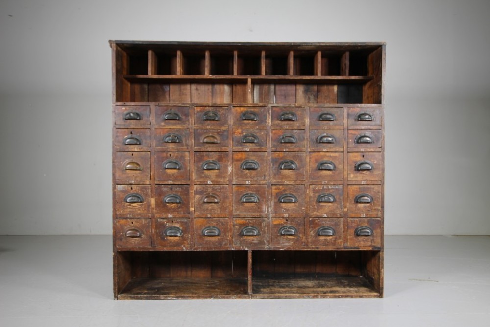 A large 19th-century pine bank of drawers featuring thirty-five small drawers with metal cup handles, top pigeonhole compartments, open bottom shelving, and a dark painted outer frame. View IX