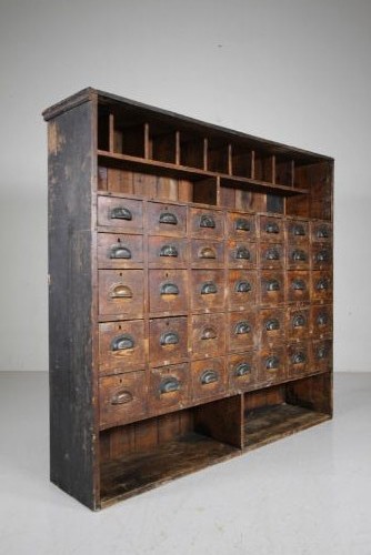 A large 19th-century pine bank of drawers featuring thirty-five small drawers with metal cup handles, top pigeonhole compartments, open bottom shelving, and a dark painted outer frame. View V