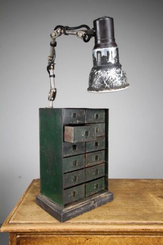 A dark green painted metal chest of twelve small drawers featuring an attached articulated industrial task lamp with a distressed shade. View VI