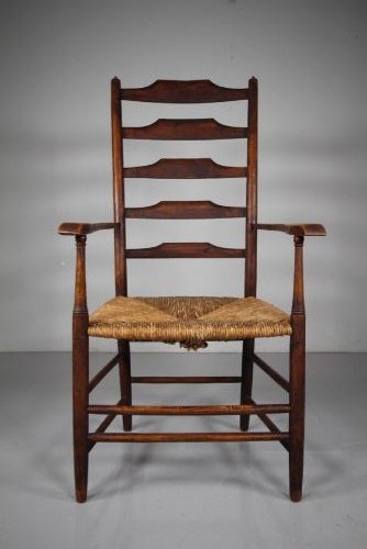 A nineteenth-century dark ash ladderback armchair featuring five horizontal back slats, sloped armrests, turned front legs, and a hand-woven rush seat. View III