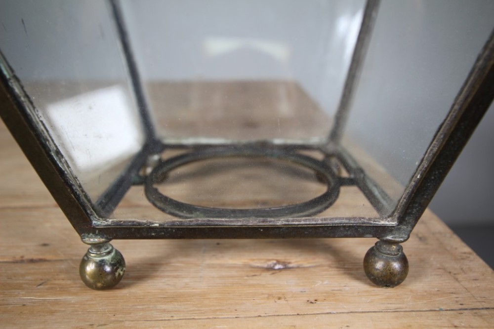 An 18th-century hanging hall lantern featuring a tapered clear glass body, dark bronze frame, detailed gilt bronze corner mounts, and suspension chains. View VI