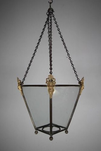 An 18th-century hanging hall lantern featuring a tapered clear glass body, dark bronze frame, detailed gilt bronze corner mounts, and suspension chains. View VII