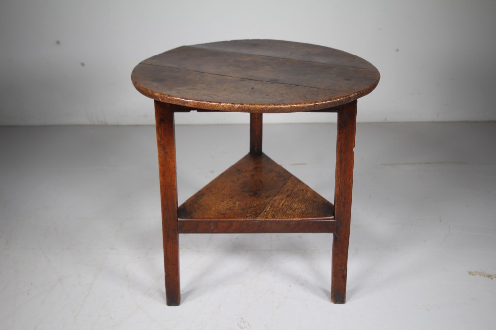 An English Georgian antique oak cricket table featuring three straight legs, a circular wooden top, and a lower triangular undertier shelf. View II