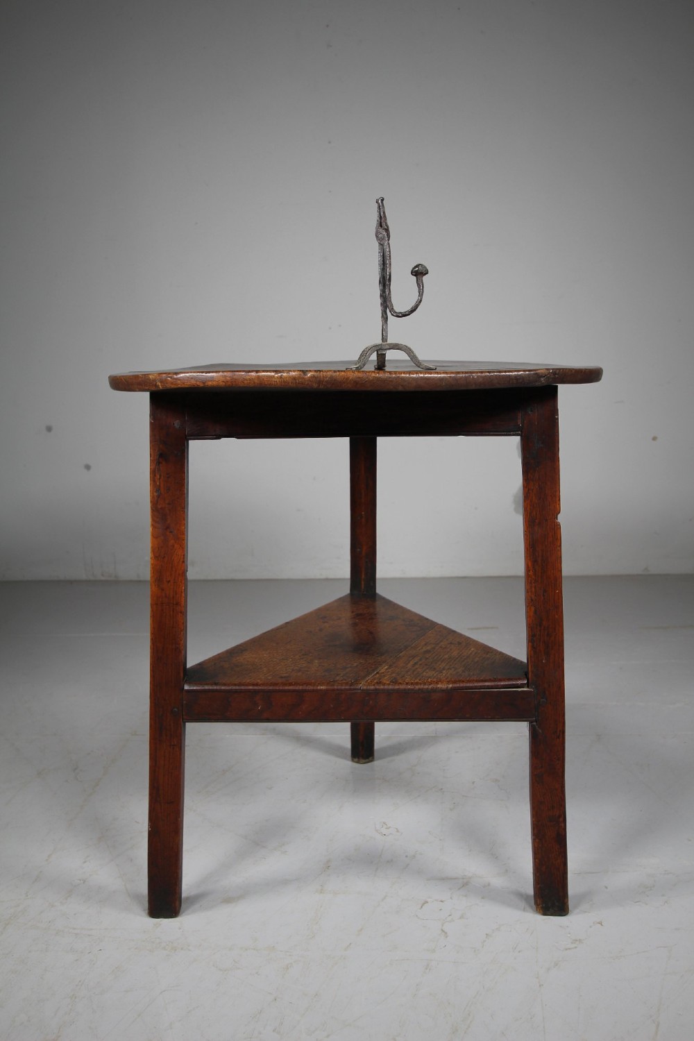 An English Georgian antique oak cricket table featuring three straight legs, a circular wooden top, and a lower triangular undertier shelf. View IV