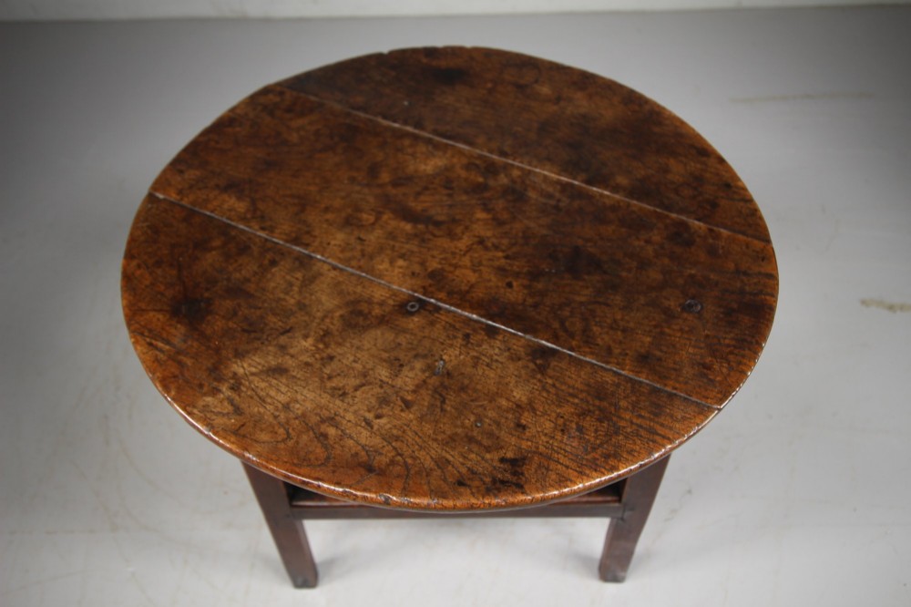 An English Georgian antique oak cricket table featuring three straight legs, a circular wooden top, and a lower triangular undertier shelf. View V