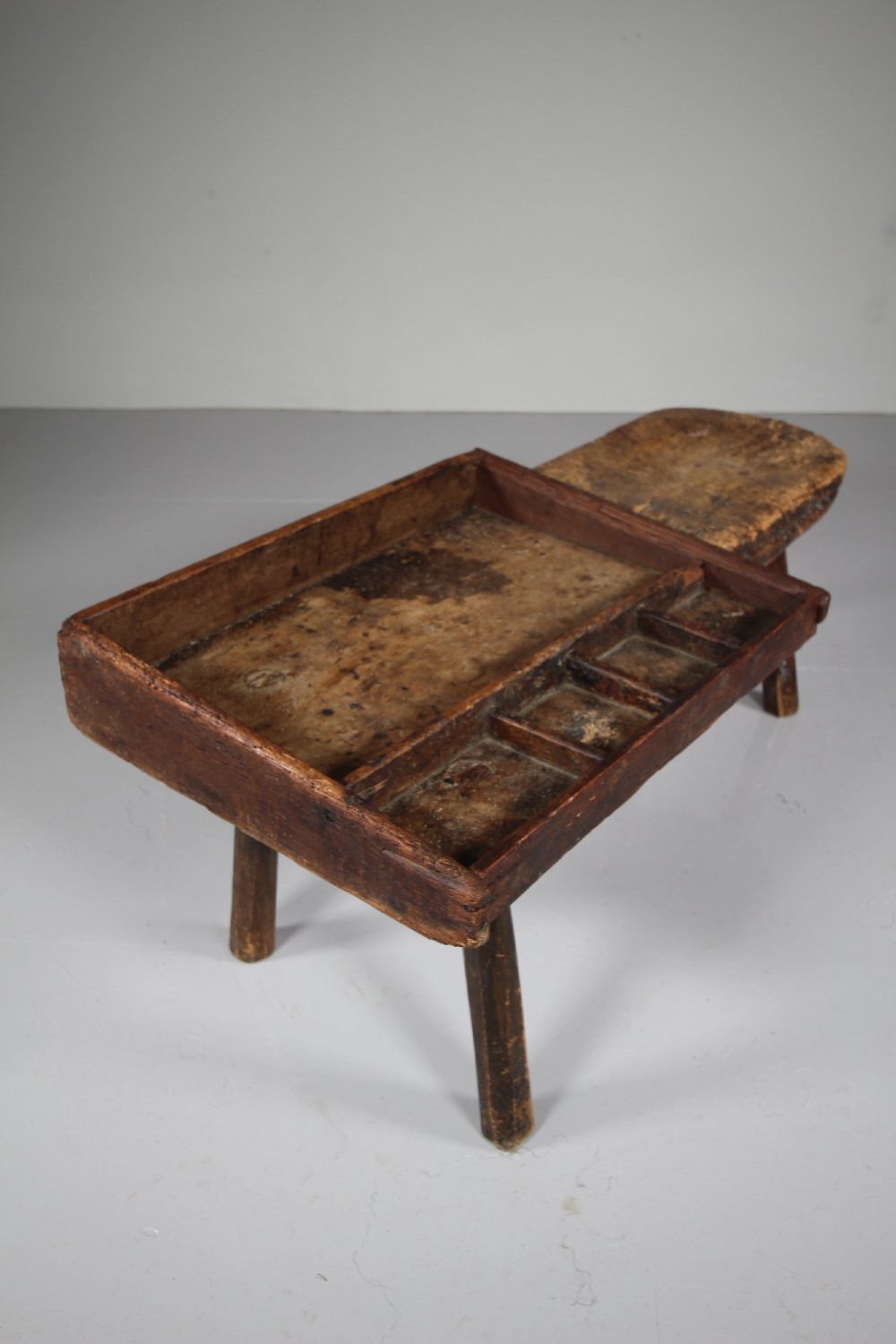 A 19th-century English wooden cobblers bench featuring a flat seating area on one side and a partitioned tray with tool compartments on splayed wooden legs. View II