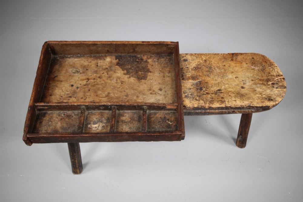 A 19th-century English wooden cobblers bench featuring a flat seating area on one side and a partitioned tray with tool compartments on splayed wooden legs. View III