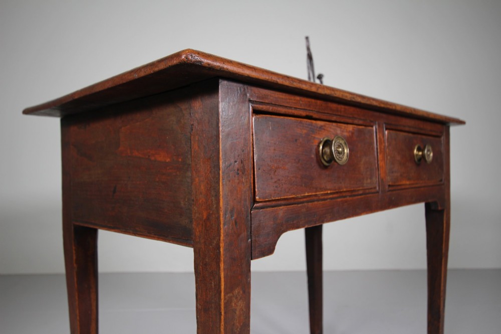 An 18th-century English side table crafted from warm brown elm and fruitwood featuring two drawers with circular brass drop handles and tapered legs. View IV