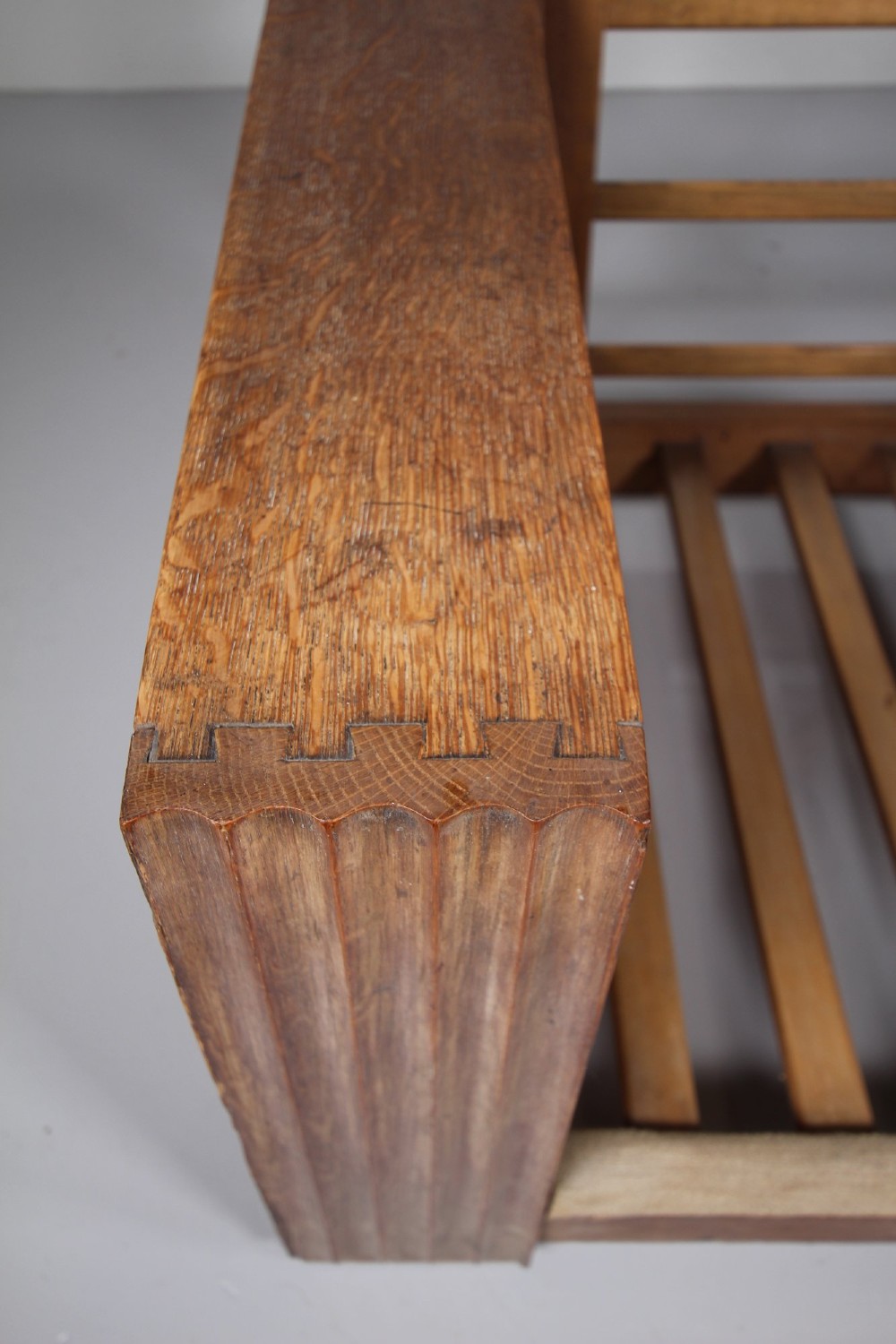 A 1930s solid oak reclining armchair frame featuring integrated side bookshelves, an adjustable slatted backrest, and a folding drop-leaf side table. View X