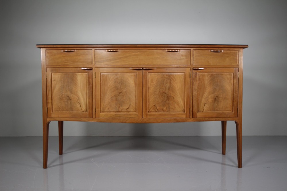 A pale walnut sideboard featuring four drawers above four cabinet doors with panelled detailing and tapered legs. View VII