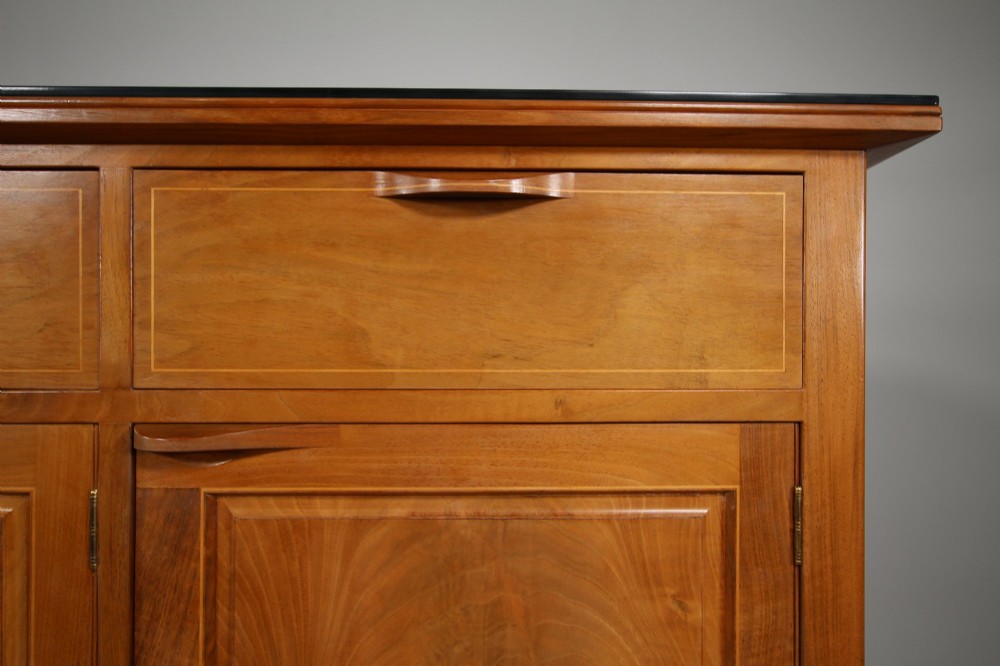 A pale walnut sideboard featuring four drawers above four cabinet doors with panelled detailing and tapered legs. View VIII