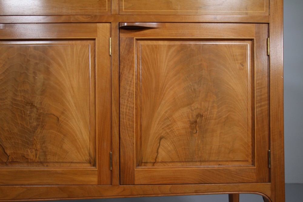 A pale walnut sideboard featuring four drawers above four cabinet doors with panelled detailing and tapered legs. View IX