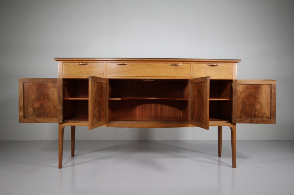 A pale walnut sideboard featuring four drawers above four cabinet doors with panelled detailing and tapered legs. View X