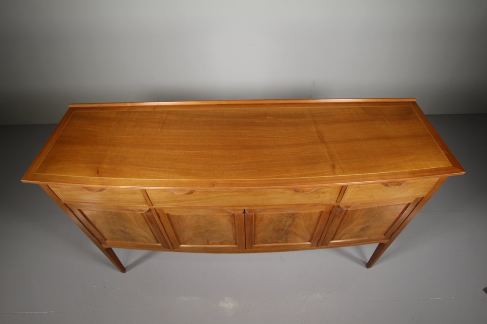 A pale walnut sideboard featuring four drawers above four cabinet doors with panelled detailing and tapered legs. View XI