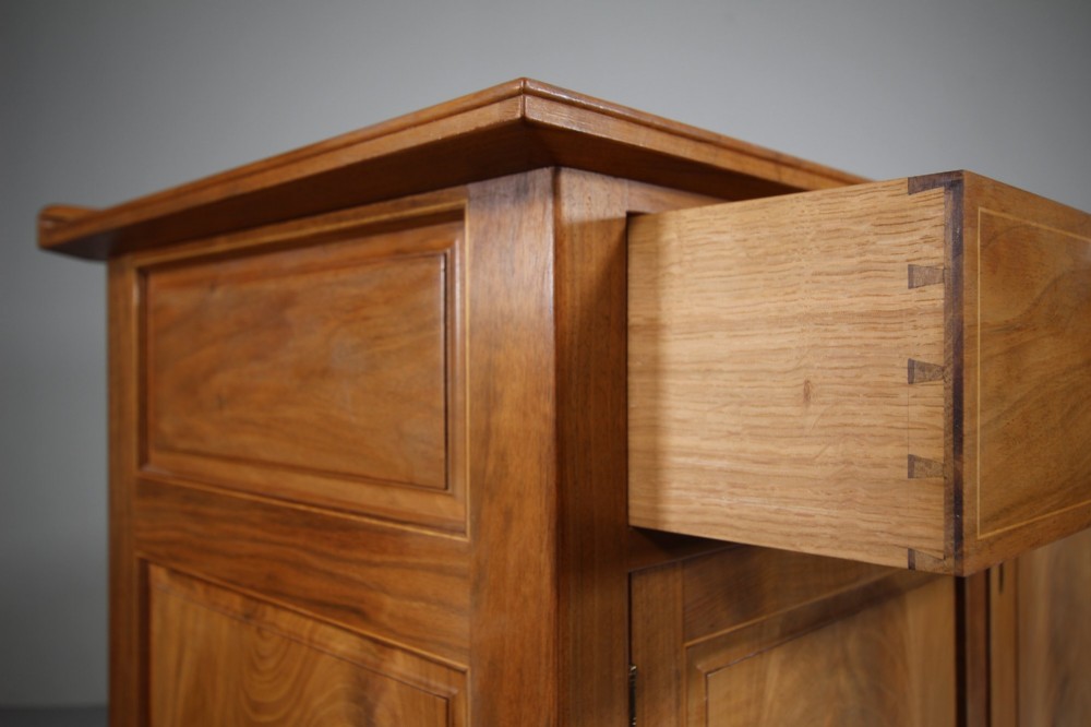 A pale walnut sideboard featuring four drawers above four cabinet doors with panelled detailing and tapered legs. View XIV