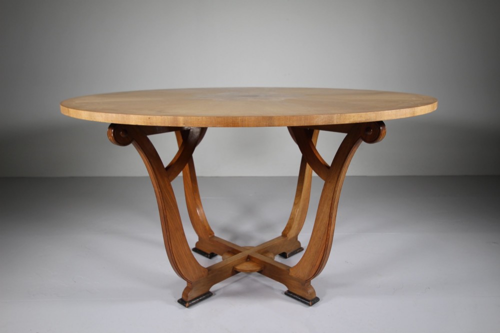 An English Art Deco circular dining table crafted from light timber with a veneered top supported by a curved four-leg pedestal base and cross stretcher. View III