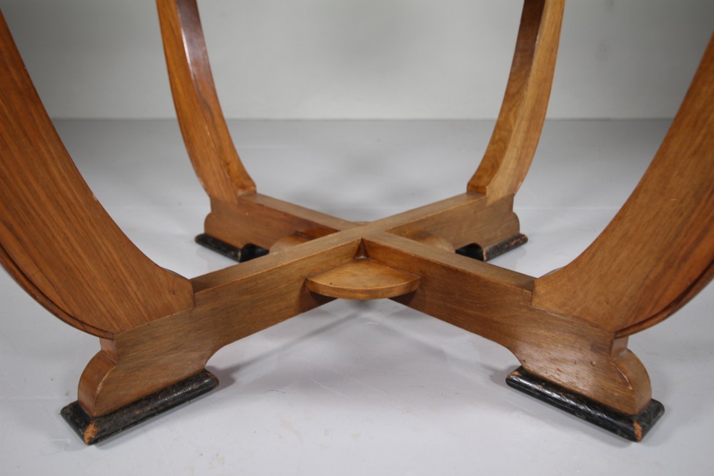 An English Art Deco circular dining table crafted from light timber with a veneered top supported by a curved four-leg pedestal base and cross stretcher. View IV
