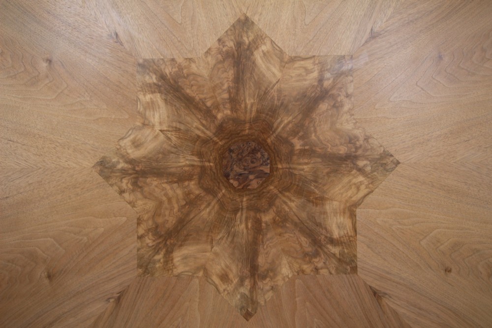 An English Art Deco circular dining table crafted from light timber with a veneered top supported by a curved four-leg pedestal base and cross stretcher. View VII