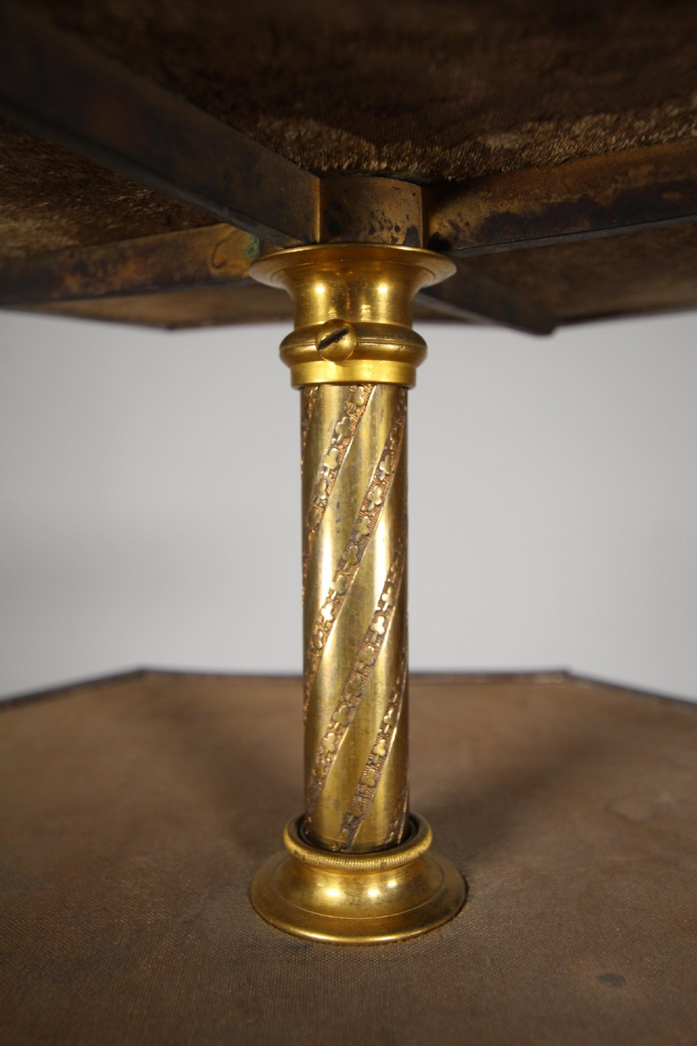 A nineteenth-century Victorian three-tiered shop display stand featuring a turned brass central column, shaped ebonised shelves, and a heavy black octagonal base. View V