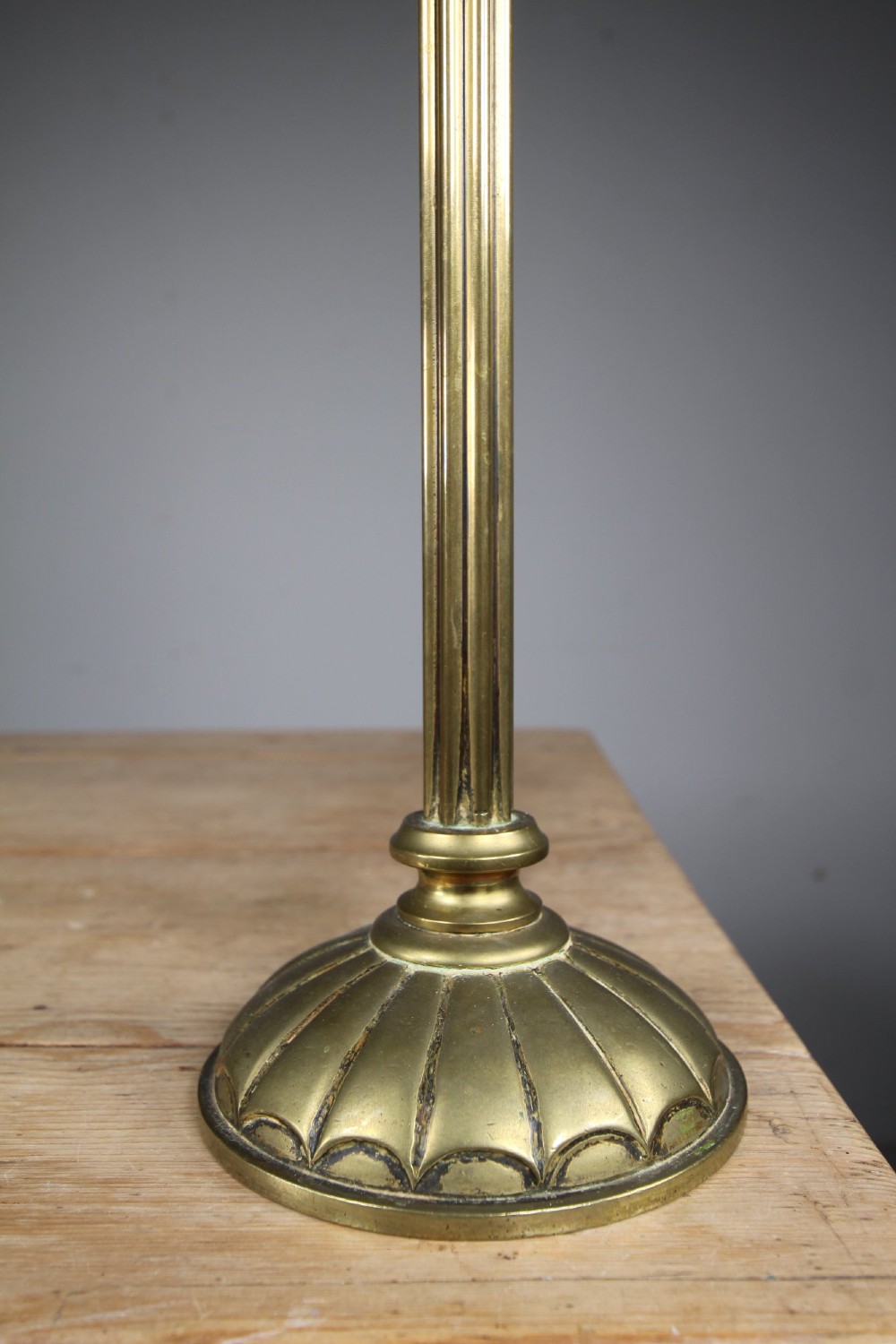 An Edwardian antique brass table lamp featuring a reeded column stem, an urn-shaped upper section, and a scalloped round base. View II