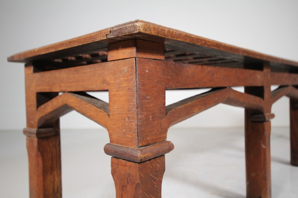 A long antique oak hall bench with a woven lattice top surface and pointed arch under-framing supported by square legs. View II