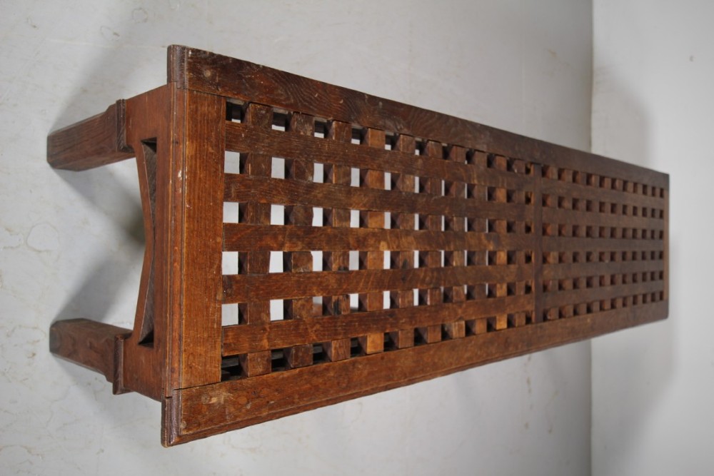 A long antique oak hall bench with a woven lattice top surface and pointed arch under-framing supported by square legs. View III