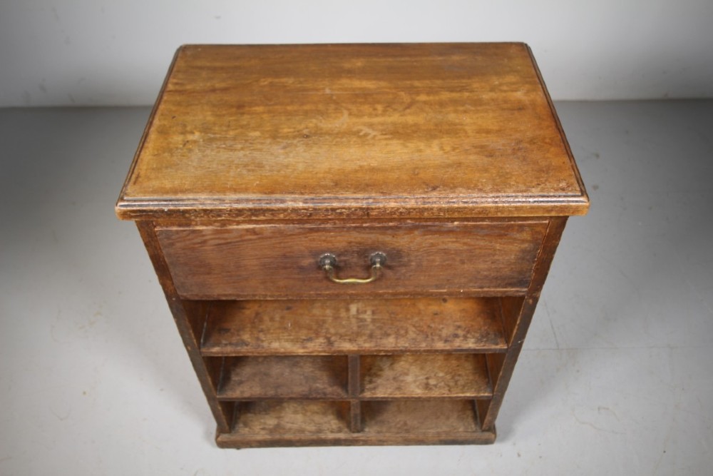 A 19th-century oak bedside cabinet with a single top drawer, brass carrying handles, and open lower pigeonhole shelves. View II