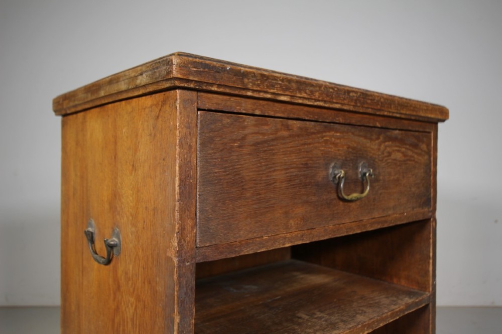 A 19th-century oak bedside cabinet with a single top drawer, brass carrying handles, and open lower pigeonhole shelves. View IV