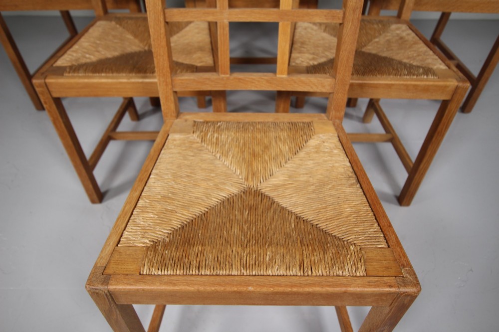 A set of six light oak dining chairs featuring geometric lattice backrests and woven seats, including two carvers with armrests. View III