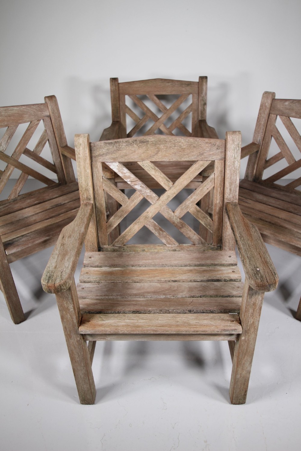 A set of four weathered teak garden armchairs with geometric Chinese Chippendale lattice backrests and square legs. View VIII
